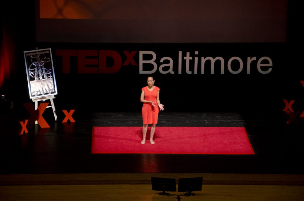 Haben Girma, sur la scène du TedX Baltimore, portant une robe rouge.
